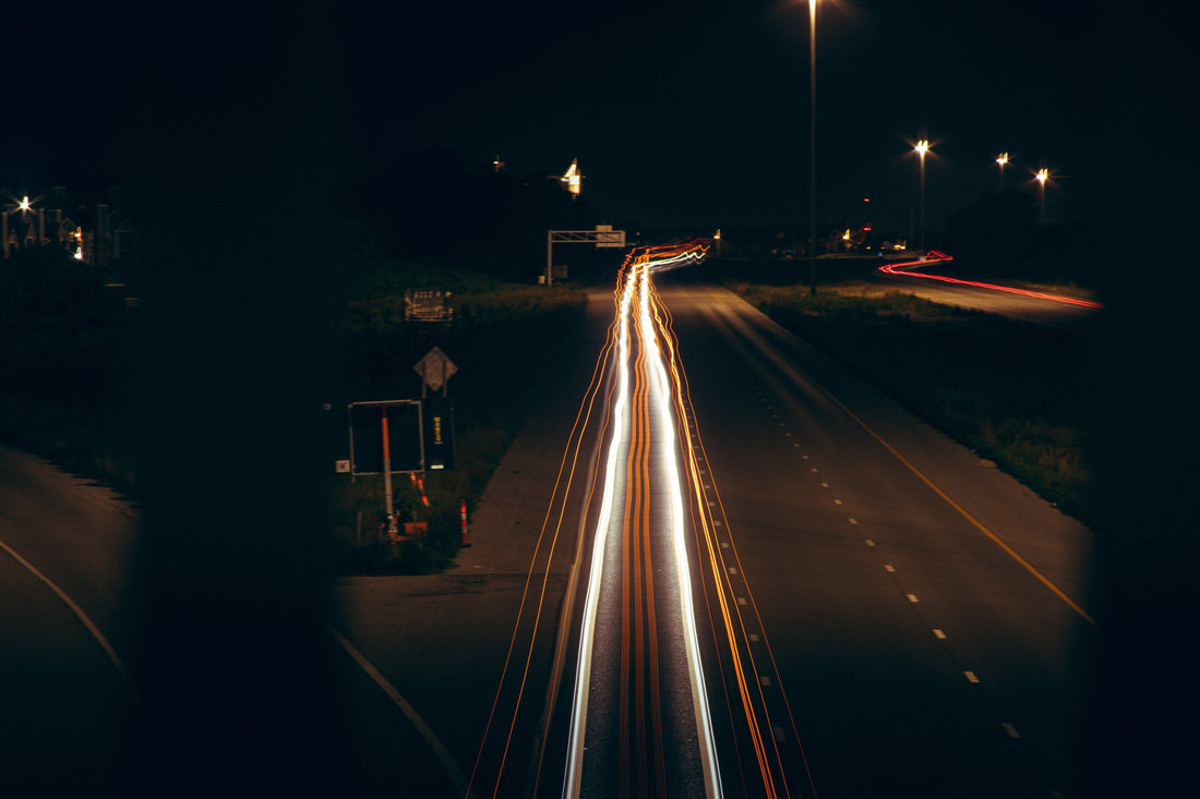 Long exposure highway shot at midnight — car headlights streaking through darkness